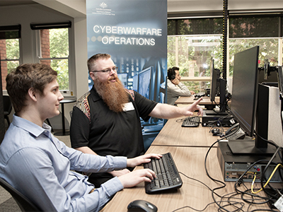 Mr Tim Pitts (DSTG) chats to IW Scholarship student Ethan Selway (University of Adelaide). Mr Tim Pitts (DSTG) chats to IW Scholarship student Ethan Selway (University of Adelaide).