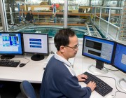 An image of a DSTG scientist at a computer, with the underwater facility in the background.