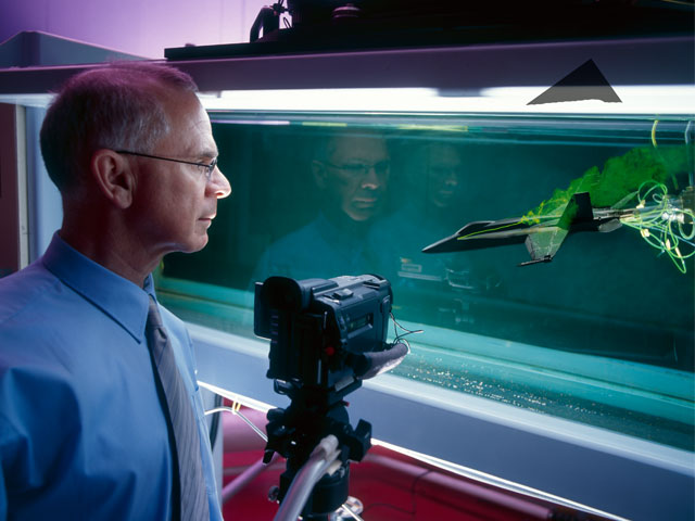 DSTG scientist Lincoln Erm studying the flow over a modern combat aircraft in the Water Tunnel. 